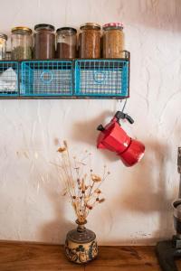 a red tea pot hanging on a wall with jars at THE HOUSE IN THE OAKS הבית באלונים in Amirim