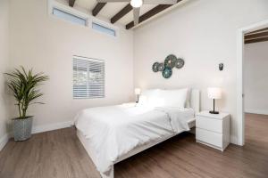 ein weißes Schlafzimmer mit einem Bett und einer Pflanze in der Unterkunft The Hideaway at Lake Ridge 3 in Fort Lauderdale