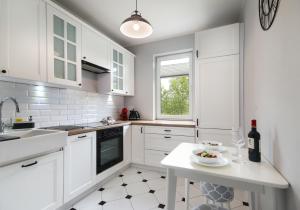 a kitchen with white cabinets and a table with a bowl of food at Apartament Rataje Park Poznań - Parking - Widok - 24h check in in Poznań