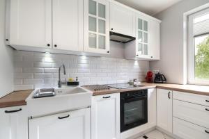 una cocina blanca con armarios blancos y fregadero en Apartament Rataje Park Poznań - Parking - Widok - 24h check in, en Poznan