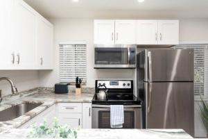 Una cocina con gabinetes blancos y un refrigerador de acero inoxidable. en The Hideaway at Lake Ridge 1, en Fort Lauderdale 13 fotos más