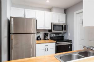 Una cocina con gabinetes blancos y un refrigerador de acero inoxidable. en The Palms at Middle River Terrace 4, en Fort Lauderdale