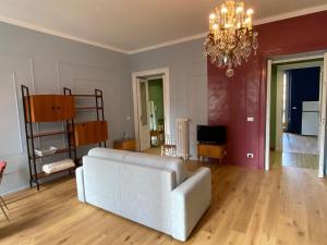 uma sala de estar com um sofá branco e um lustre em casa liberty Di&Pi em Turim