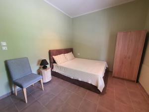 a small bedroom with a bed and a chair at Lotaki the friendly house in Limenaria