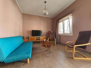 a living room with a blue couch and a tv at Lotaki the friendly house in Limenaria