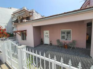 a pink house with a white fence and chairs at Lotaki the friendly house in Limenaria