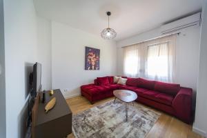 Una sala de estar con un sofá rojo y un televisor. en SUN apartment, en Podgorica
