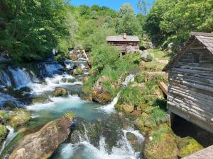 a river with a house next to a waterfall at Villa Pampas in Banja Luka