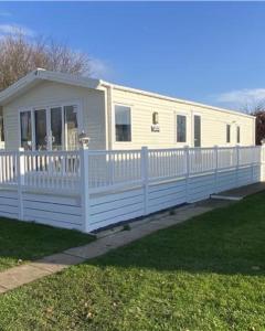 a white mobile home with a white fence at 6 Berth Comfy Homely Caravan, Dog Friendly in Belton