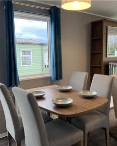 uma mesa de jantar com cadeiras e uma grande janela em 6 Berth Comfy Homely Caravan, Dog Friendly em Belton