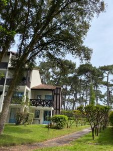 un grand bâtiment blanc avec des arbres devant lui dans l'établissement Appartement du Golf Les Bastides piscine et océan, à Moliets-et-Maa
