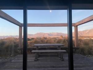 a picnic table on a porch with a view of the mountains at Mackenzie Crib in Lake Tekapo