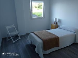 1 dormitorio con 1 cama, 1 silla y 1 ventana en Nuevo apartamento Montelouro en Louro