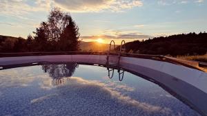 a reflection of the sunset in a pool of water at Bojkówka Domki Wypoczynkowe in Baligród