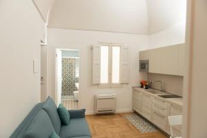 a living room with a blue couch and a kitchen at Le Dimore di Puglia - Palazzo Ladogana in Monopoli