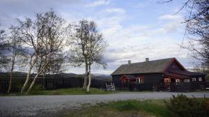 a red and black house with a fence and trees at Snøhetta Camping in Hjerkinn