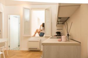 a woman sitting in a window in a kitchen at Le Dimore di Puglia - Palazzo Ladogana in Monopoli