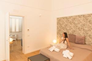 a woman sitting on a bed in a room at Le Dimore di Puglia - Palazzo Ladogana in Monopoli