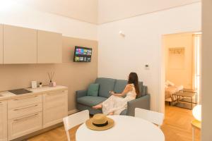 a woman sitting on a couch in a living room at Le Dimore di Puglia - Palazzo Ladogana in Monopoli