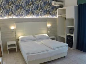 una camera da letto con letto, lenzuola e cuscini bianchi di Hotel Gardenia a Caorle
