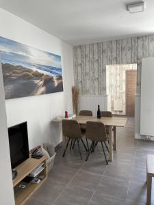 a dining room with a table and chairs and a television at Middelbeach in Middelkerke