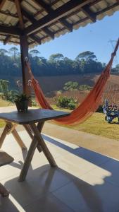 a hammock and a table with a view of a river at Vale do Sossego Chalés in Domingos Martins