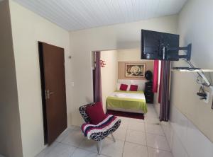 um quarto com uma cama e uma cadeira num quarto em Cantinho Morro Branco em Beberibe