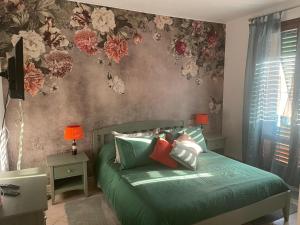 sypialnia z zielonym łóżkiem z kwiatami na ścianie w obiekcie The Loft E&E Chianti Room w mieście Empoli