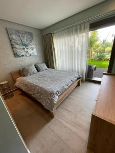 a bedroom with a bed and a large window at Appartement haut standing avec piscine Mohammedia in Mohammedia