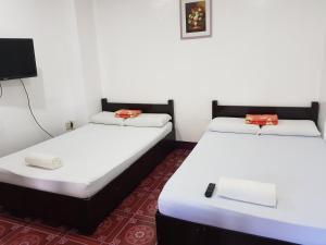 two twin beds in a room with a tv at Pabua's Cottages in Mambajao