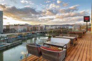 balcón con mesas y sillas y vistas al río en Radisson RED Hotel, Vienna, en Viena