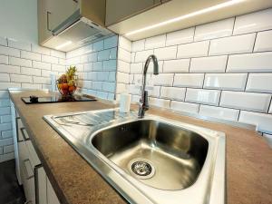 un fregadero de acero inoxidable en una cocina con azulejos blancos en Apartments Sunset en Mlini