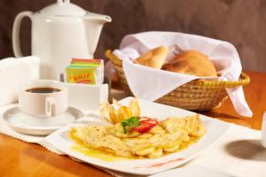 a plate of food with a cup of coffee and a basket of bread at Hotel Los Tambos Colonial in Arequipa