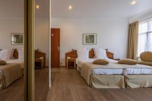 een hotelkamer met 2 bedden en een spiegel bij Hotel Geerts in Westerlo