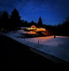 a lit up house in the snow at night at The Blue House On The Hill Catskills—Views in Claryville