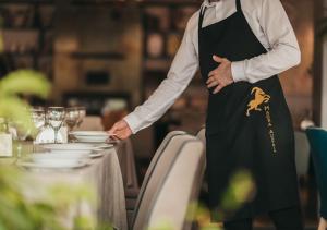 a chef standing in front of a table in a restaurant at Magra Austria Hotel & Restaurant Prishtine in Pristina