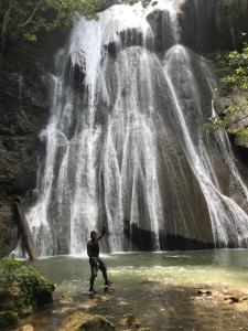 Pulau Mansuar的住宿－TABARI DIVE LODGE，站在瀑布前的水域上的人