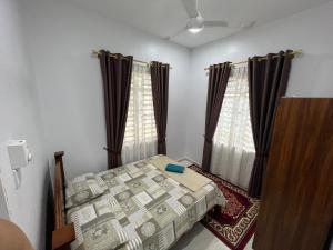 a bedroom with a bed and two windows at FADI BEACH GUESTHOUSE in Kampong Sura Masjid