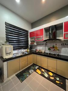 a kitchen with red cabinets and a kitchen rug at FADI BEACH GUESTHOUSE in Kampong Sura Masjid