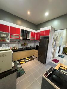 a kitchen with red cabinets and a black refrigerator at FADI BEACH GUESTHOUSE in Kampong Sura Masjid