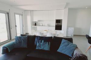 a living room with a black couch and a kitchen at Brisa do Mar Ap. in Nazaré