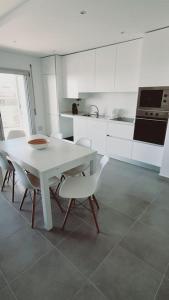 a white kitchen with a white table and chairs at Brisa do Mar Ap. in Nazaré