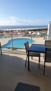 a blue table and chairs on a balcony with a swimming pool at Brisa do Mar Ap. in Nazaré