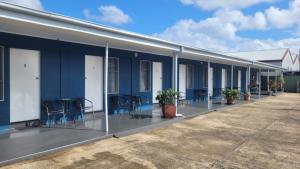 ein blaues Gebäude mit Stühlen und Tischen davor in der Unterkunft Innisfail City Motel in Innisfail