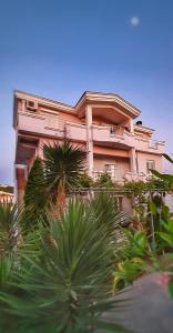 una gran casa rosa con palmeras delante en Apartments Perezaj, en Ulcinj