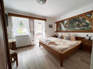 a bedroom with a large bed and two windows at PENSION POD SKALOU in Hřensko