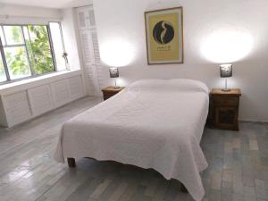 a bedroom with a white bed and two lamps at casa HIKURI in Cancún