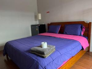 a bed with a pink and purple blanket and a towel at SMILE HOME GUESTHOUSE in Rayong