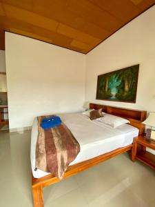 a bed in a room with a painting on the wall at Radya Homestay in Nusa Lembongan