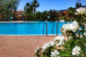 - une piscine avec des fleurs blanches en face dans l'établissement Duplex Atlas Golf Resort Pοοl νieω Seriniτყ & Cαlm, à Marrakech